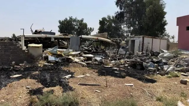 حطام متناثر على الأرض، وتظهر أشجار خلف الدمار