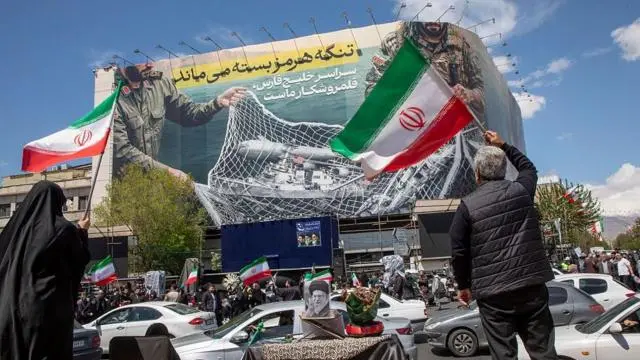 إيرانوين يرفعون الأعلام الوطنية أثناء تجمعهم في ساحة الثورة بطهران بعد اتفاق الولايات المتحدة وإيران على وقف إطلاق النار لمدة أسبوعين، في 8 أبريل/ نيسان 2026 في العاصمة الإيرانية طهران.