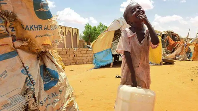 فتاة سودانية تتفاعل وهي تحمل عبوة بلاستيكية في مخيم الرحمانية للنازحين، بالقرب من مدينة الأبيض في منطقة كردفان الجنوبية